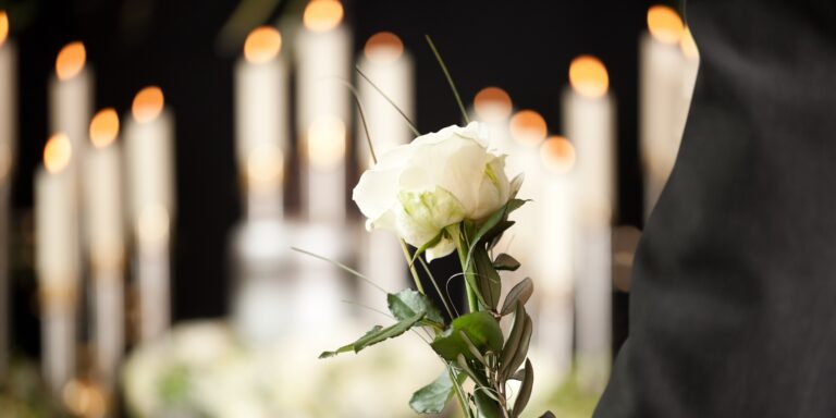 Grief - man with white roses at urn funeral